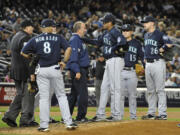 A Seattle Mariners trainer comes to the mound to check on starting pitcher Felix Hernandez (34) after the Mariners pitcher aggravated his sore back.