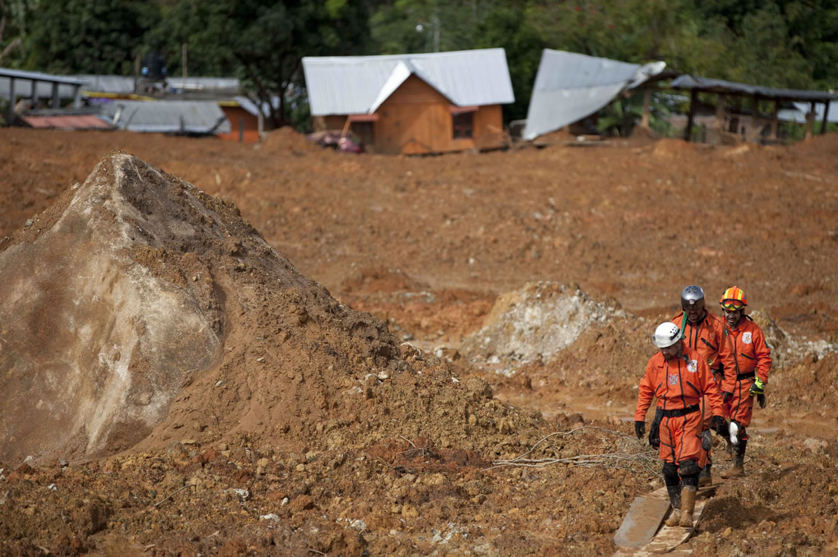 Rescue workers walk over mud at the site of a landslide in the village of La Pintada, Mexico, Sunday Sept. 22, 2013. The Mexican army's emergency response and rescue team continued searching for victims and assessing the damage Sunday from the one-two punch of storms Manuel and Ingrid in La Pintada where a landslide wiped out half of the town and 68 people remained missing.