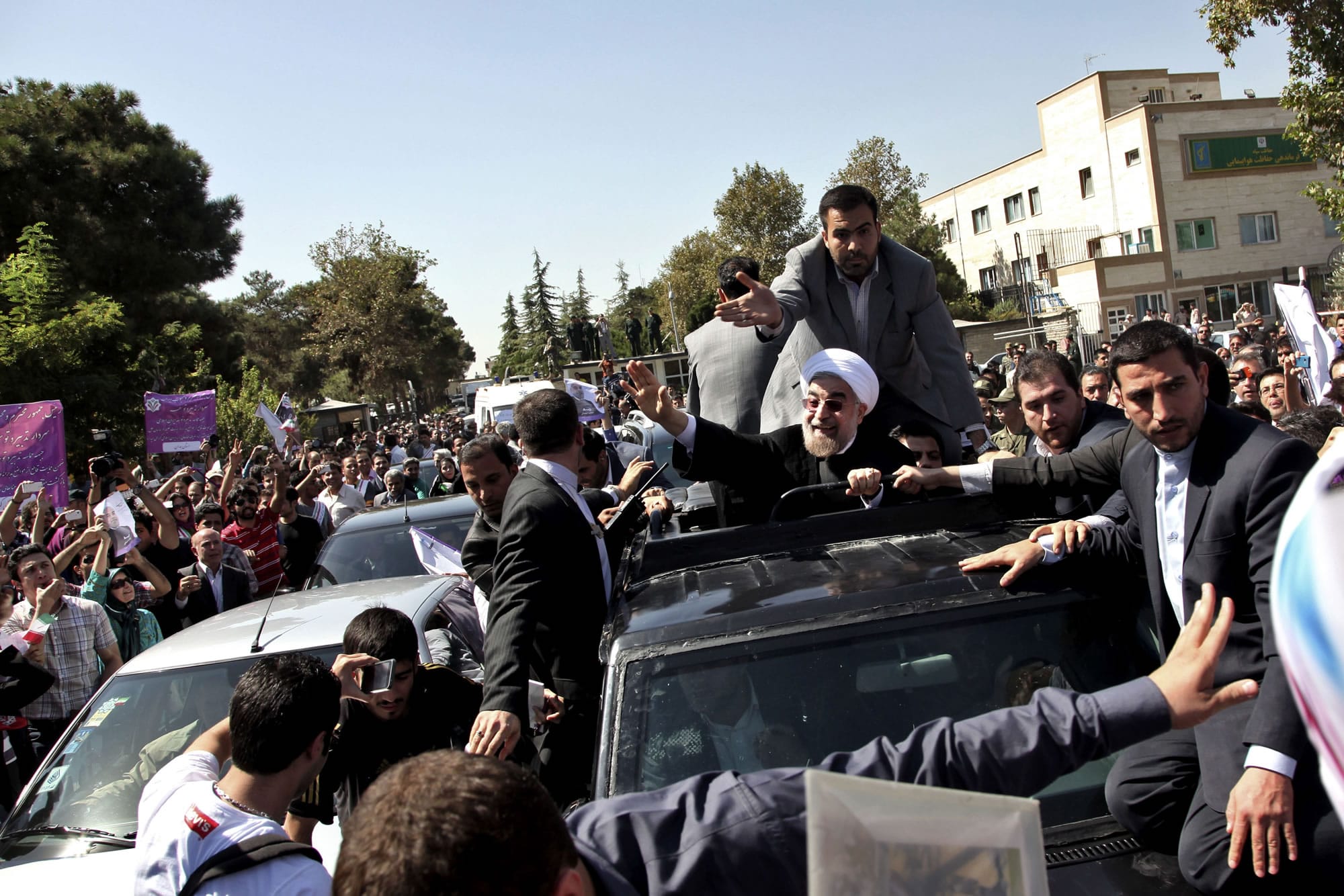 Iranian President Hassan Rouhani, center, waves to supporters upon his arrival from the US near the Mehrabad airport in Tehran, Iran, Sept. 28, 2013. Iranians from across the political spectrum hailed Saturday the historic phone conversation between President Barack Obama and Rouhani, reflecting wide support for an initiative that has the backing of both reformists and the country's conservative clerical leadership.