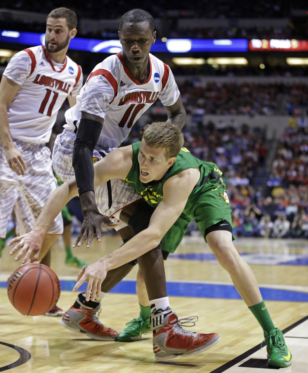 Oregon forward E.J. Singler passes the ball around Louisville center Gorgui Dieng (10) during the second half  Friday.