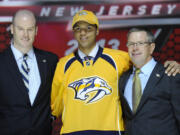 Portland Winterhawks Seth Jones stands with officials from the Nashville Predators after being chosen 4th overall in the first round of the NHL hockey draft on Sunday.