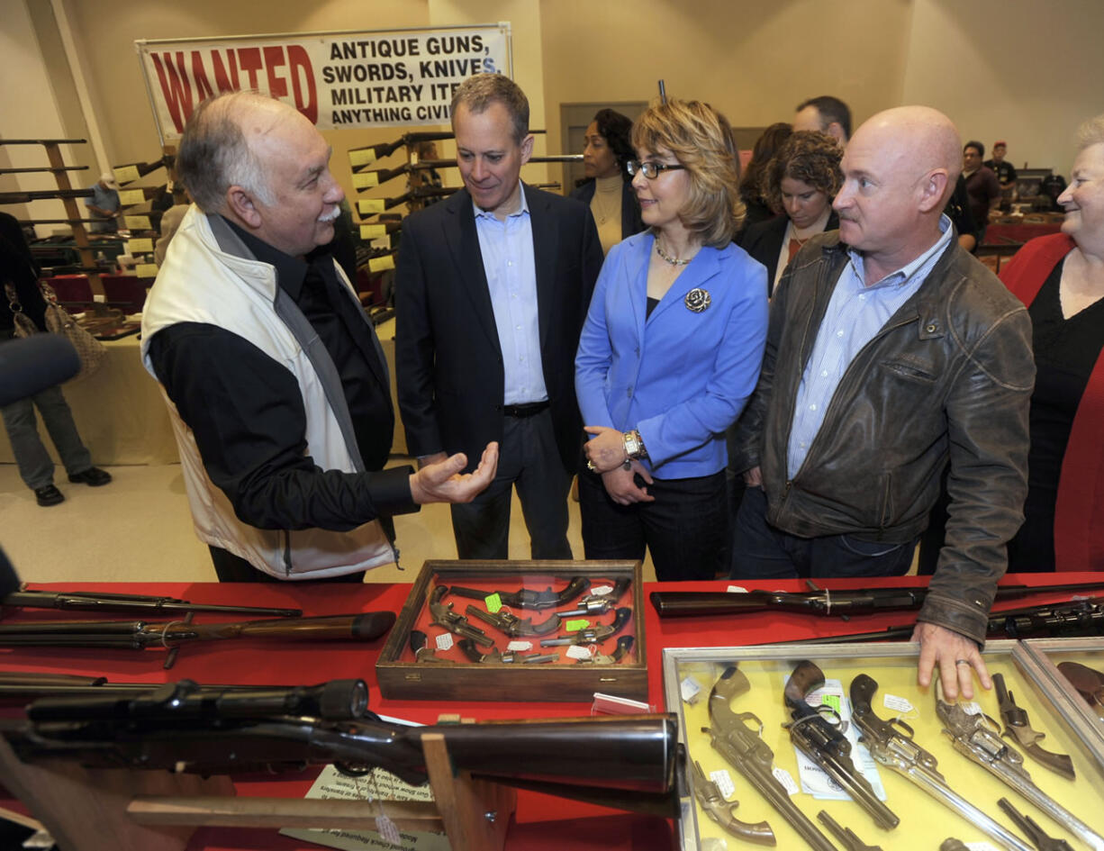 Gun show organizer Dave Petronis, left, leads New York Attorney General Eric Schneiderman, second from left, former Arizona congresswoman Gabrielle Giffords, second from right, and her husband Mark Kelly on a tour of the New EastCoast Arms Collectors Associates arms fair in Saratoga Springs, N.Y.