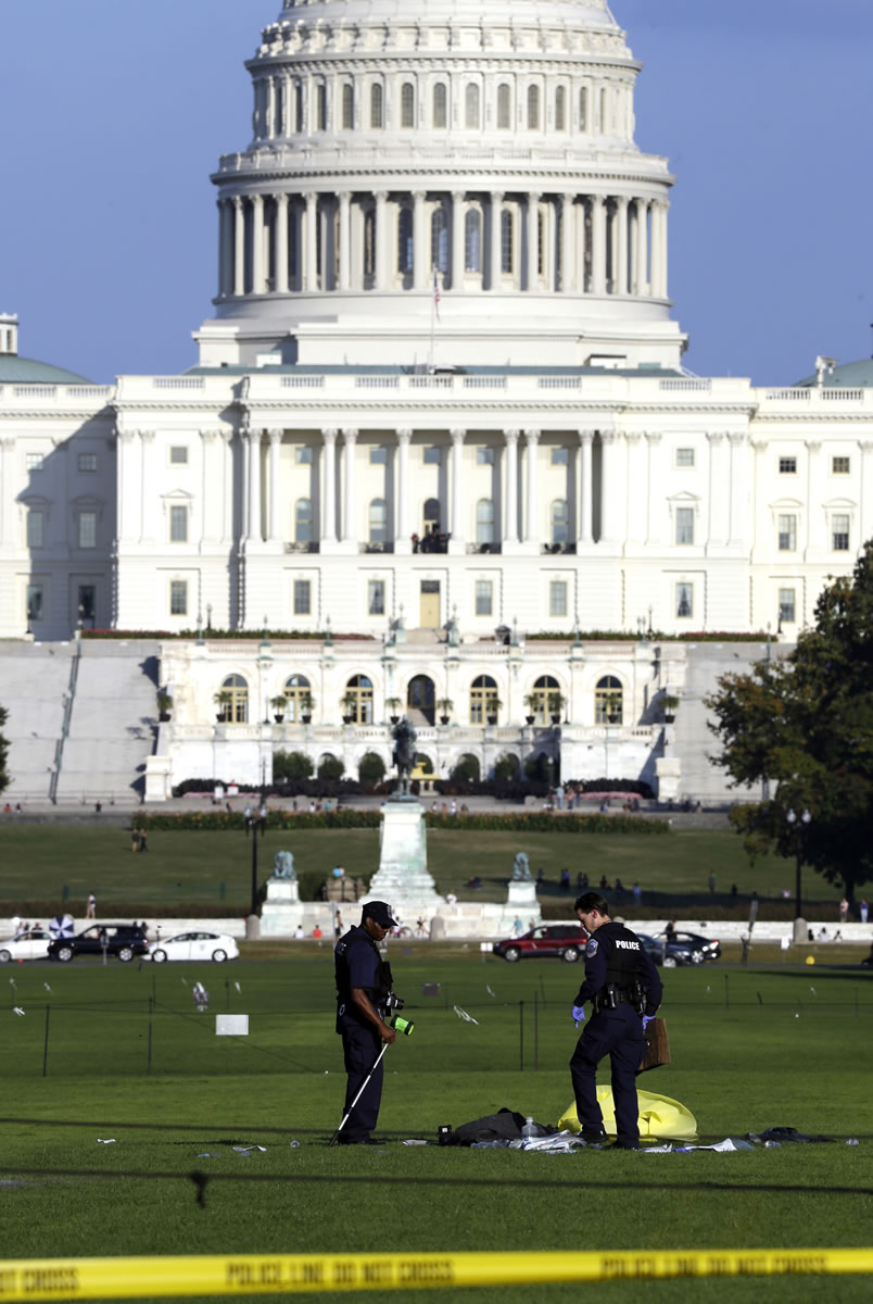 Law enforcement officers investigate the scene on the National Mall in Washington where, according to a fire official, a man set himself on fire Friday.