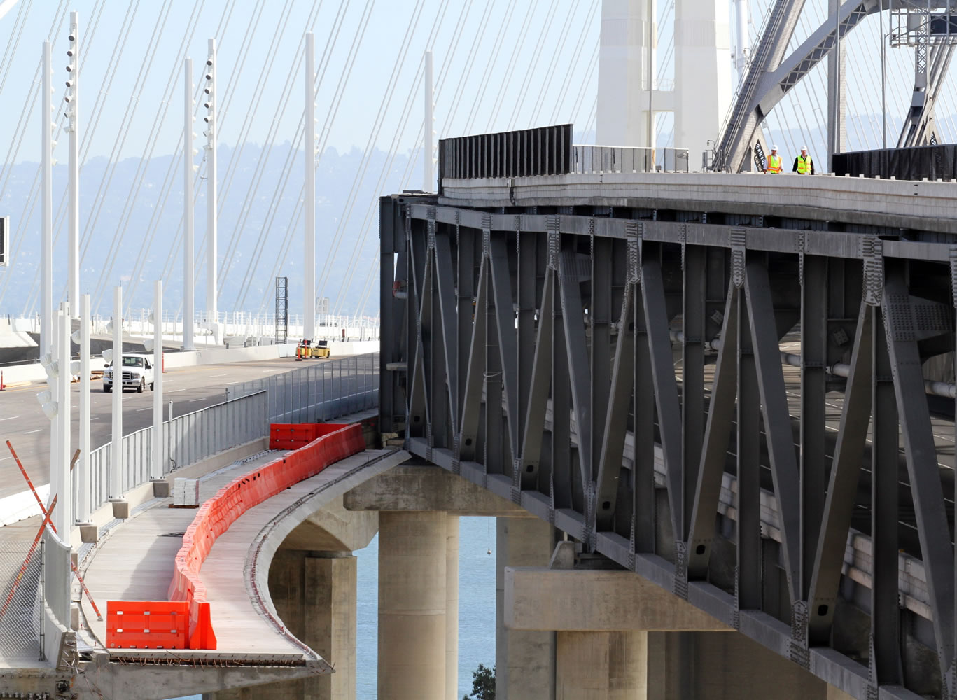 Workers walk on the old cantilever bridge, top right, where the new and the old come together Friday during the Bay Bridge closure in Oakland, Calif.