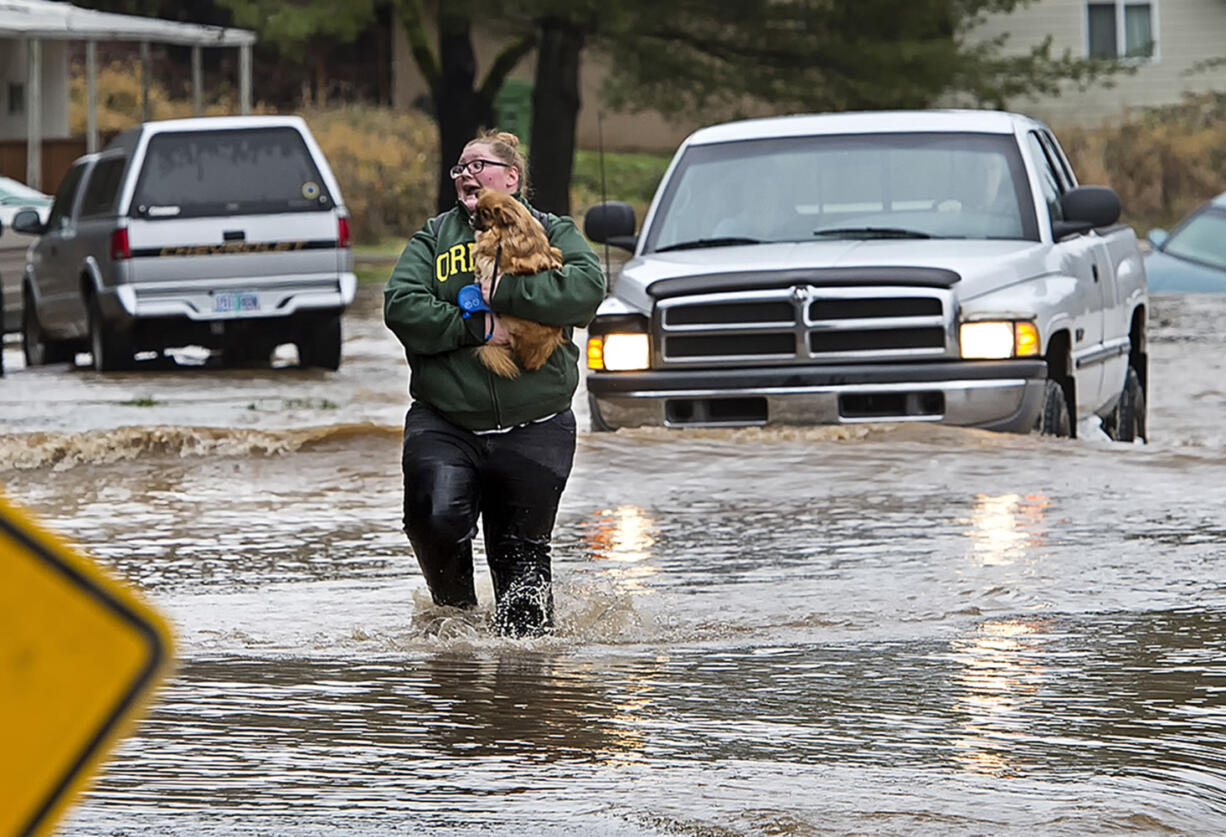 Cherise Giberson carries one of her family&#039;s pets, they have three dogs, three puppies and a hedgehog, that was rescued from their flooded home in the Swedetown Village mobile home park in Clatskanie, Ore., on Wednesday, Dec. 9, 2015. The water was freezing and the current swift when she was thigh-deep in the rain-swollen river that overflowed its banks and inundated the homes.