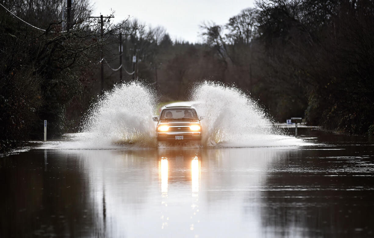 A truck drives through high water from the Marys River in Philomath, Ore., on Friday Dec. 18, 2015. Fresh storms barreled through the already sodden Pacific Northwest on Friday, triggering a landslide that killed a woman near the Oregon Coast and clogging mountain passes in the Washington Cascades.