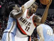 Portland Trail Blazers forward LaMarcus Aldridge (12) pulls in a rebound against Denver Nuggets forward Kenneth Faried, left, and center Kosta Koufos (41), of Russia, during the first half of their preseason NBA basketball game Wednesday, Oct.