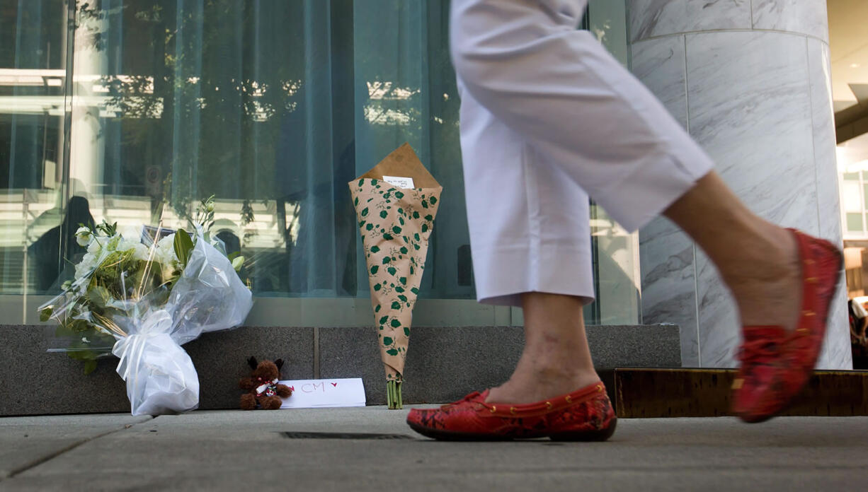 A woman walks past a small memorial Sunday for Canadian actor Cory Monteith outside the Fairmont Pacific Rim Hotel where he died on Saturday in Vancouver, B.C.