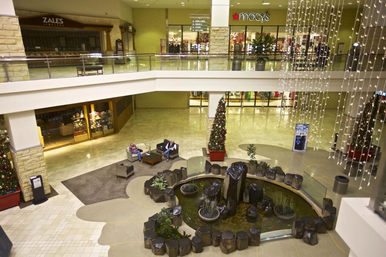 Shoppers sit in chairs in front of the fountain at the Clackamas Town Center mall as it opens Friday in Portland. The mall reopened three days after a gunman killed two people and wounded a third amid a holiday shopping crowd estimated at 10,000.