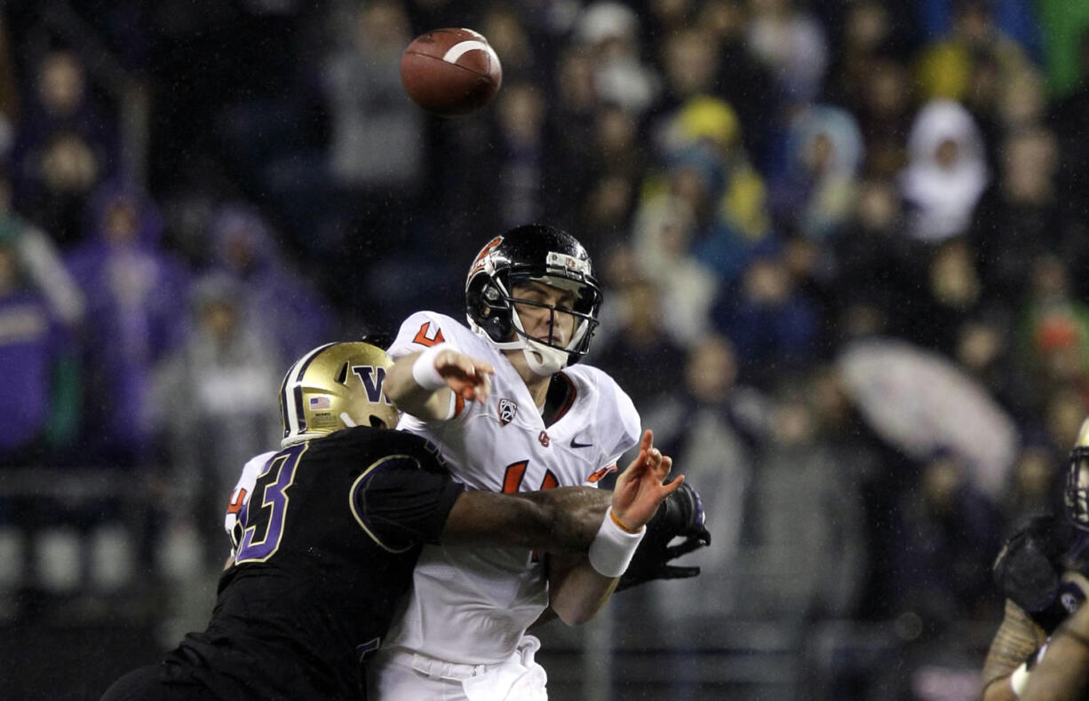 Oregon State quarterback Sean Mannion is hit by Washington's Andrew Hudson as he throws in the first half Saturday.