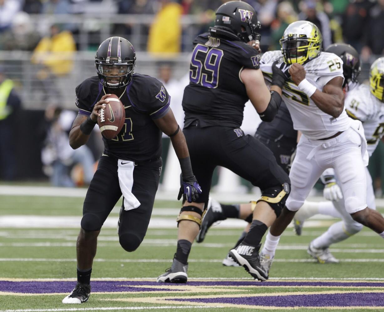 Washington quarterback Keith Price, left, rushes against Oregon in the first half of an NCAA college football game, Saturday, Oct. 12, 2013, in Seattle.