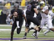 Washington quarterback Keith Price, left, rushes against Oregon in the first half of an NCAA college football game, Saturday, Oct. 12, 2013, in Seattle.