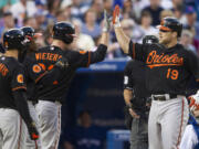 Baltimore Orioles' Chris Davis, right, is congratulated by Matt Wieters, center, Adam Jones, center left,  and Nick Markakis after hitting a three-run homer as Toronto Blue Jays catcher Josh Thole looks on during the sixth inning of a baseball action in Toronto on Friday, June 21, 2013.