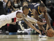 Portland Trail Blazers guard Damian Lillard (0) reaches for a loose ball against Indiana Pacers guard Rodney Stuckey (2) during the second half of an NBA basketball game in Portland, Ore., Thursday, Dec. 3, 2015. The Trail Blazers won 123-111.