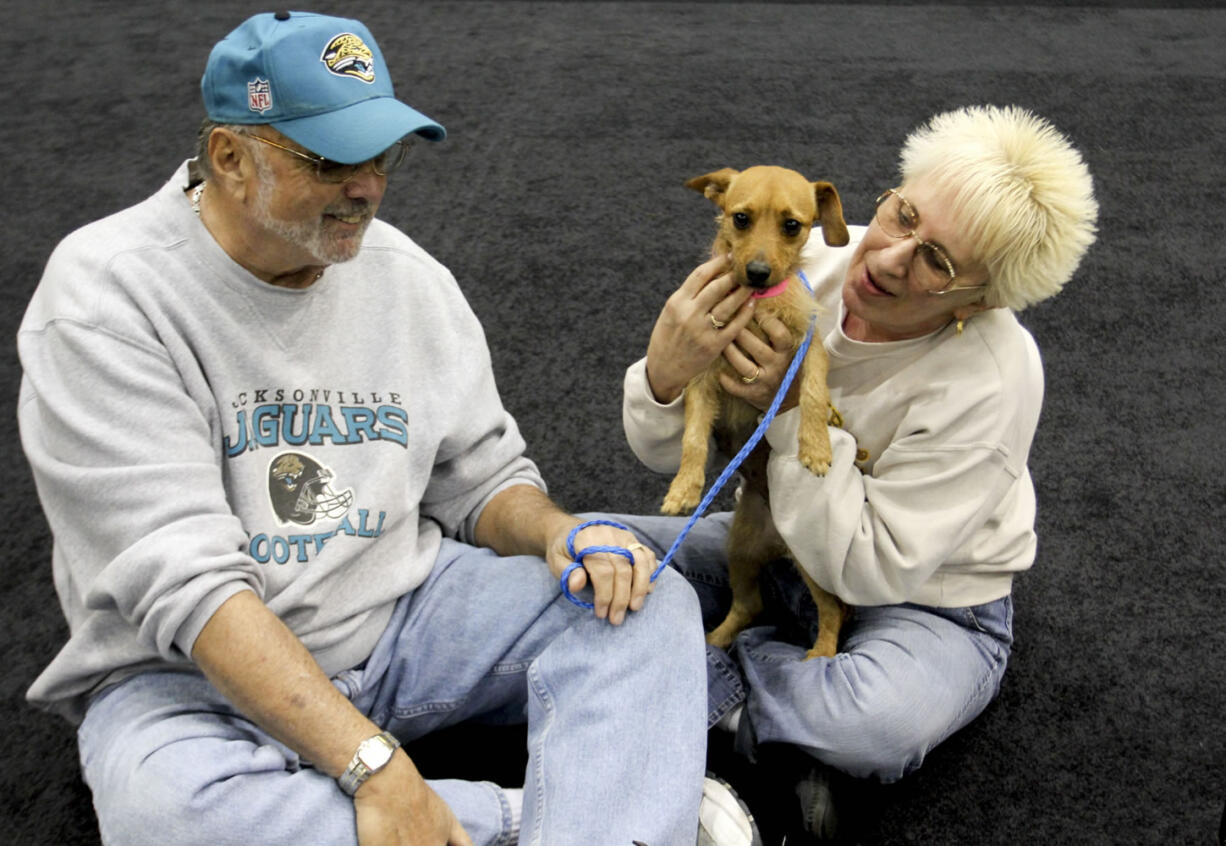 This Dec. 11, 2012 photo provided by MGM Resorts International shows MGM Grand poker dealer Dar Reike holds her adopted dog, Alexia, next to her husband, Rick Reike. They adopted the dog, at a company adoption fair last year. However, they decided against getting pet insurance. Through MGM Resorts International, they could have gotten a major medical policy for $25 to $35 a month. With one dog, she would have also gotten a 5 percent discount.