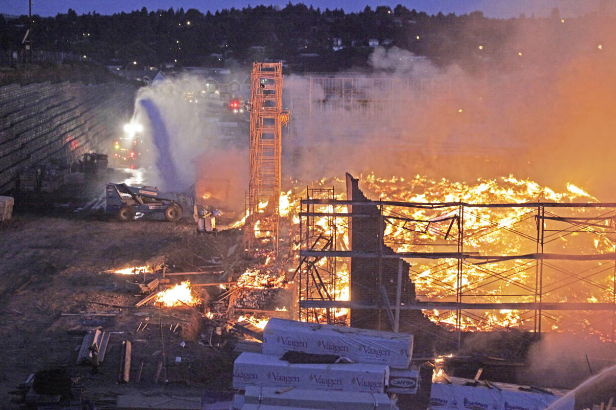 Firefighters work to contain a fire at the unoccupied Grove Apartments complex in Pullman early July 14.