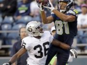 Seattle's Golden Tate (81) catches the ball in front of Oakland's Shawntae Spencer, but later left the game after being tackled on a punt return.