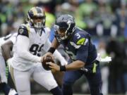 Seattle Seahawks quarterback Russell Wilson (3) is chased by St. Louis Rams' William Hayes in the first half of an NFL football game, Sunday, Dec. 27, 2015, in Seattle.