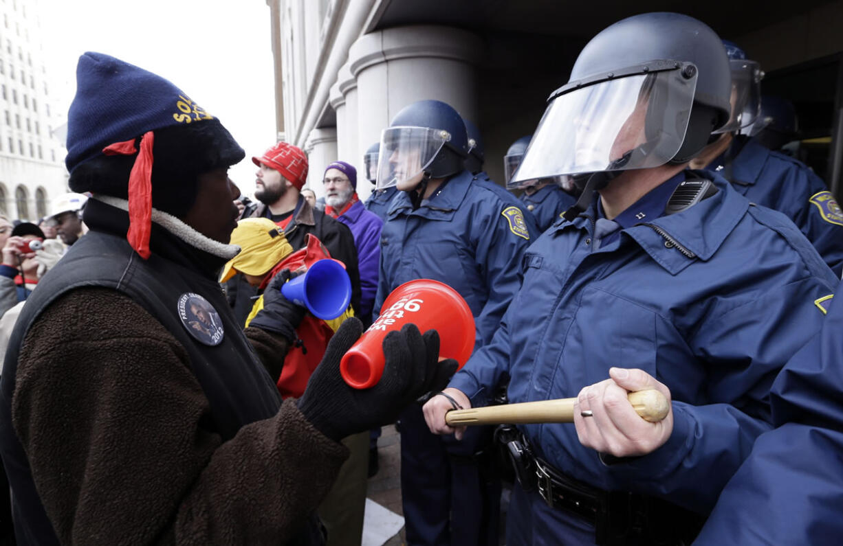 A protester rallies in front of Michigan State Police at the George W. Romney State Building, where Gov.