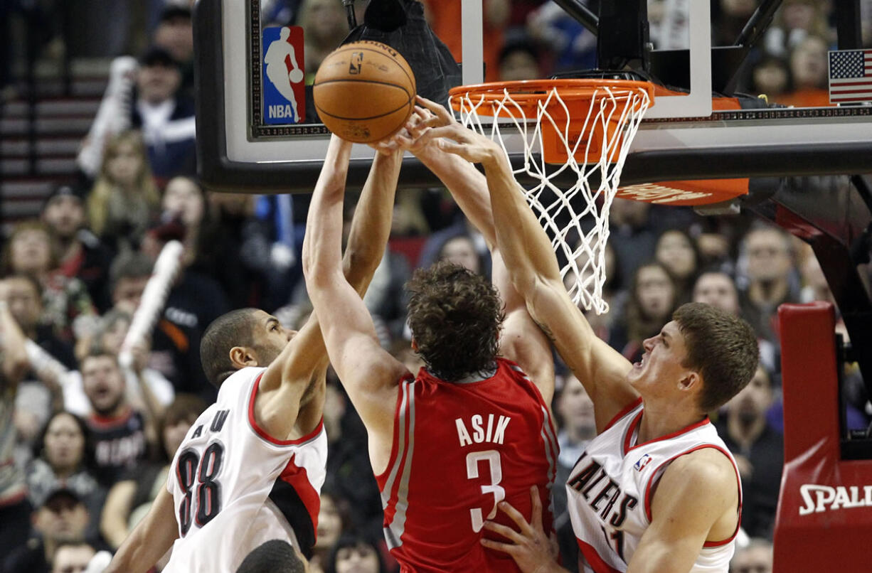 Houston Rockets center Omer Asik (3) has his shot rejected by the Portland Trail Blazers' Meyers Leonard, right, and Nicolas Batum during overtime on Friday.