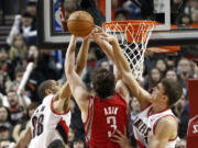 Houston Rockets center Omer Asik (3) has his shot rejected by the Portland Trail Blazers' Meyers Leonard, right, and Nicolas Batum during overtime on Friday.