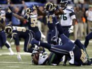 Seattle Seahawks running back Marshawn Lynch lands on his back as he is stopped on fourth down and St. Louis Rams players celebrate on the final play in overtime on Sunday, Sept. 13, 2015, in St. Louis. The Rams won 34-31.