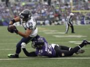 Seattle Seahawks wide receiver Doug Baldwin (89) scores a touchdown as he is tackled by Baltimore Ravens defensive back Shareece Wright (35) during the first half an NFL football game, Sunday, Dec. 13, 2015, in Baltimore.