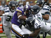 Minnesota Vikings running back Adrian Peterson (28) is stopped by Seattle Seahawks defenders including  linebacker Bobby Wagner (54) and strong safety Kam Chancellor (31)in the first half of an NFL football game Sunday, Dec. 6, 2015 in Minneapolis.