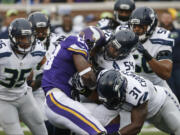 Vikings running back Adrian Peterson (28) is stopped by Seahawks defenders including  Bobby Wagner (54) and Kam Chancellor (31).