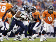 Denver quarterback Peyton Manning (18) looks on as Seattle's K.J. Wright, center, runs back an interception in the first half Saturday.