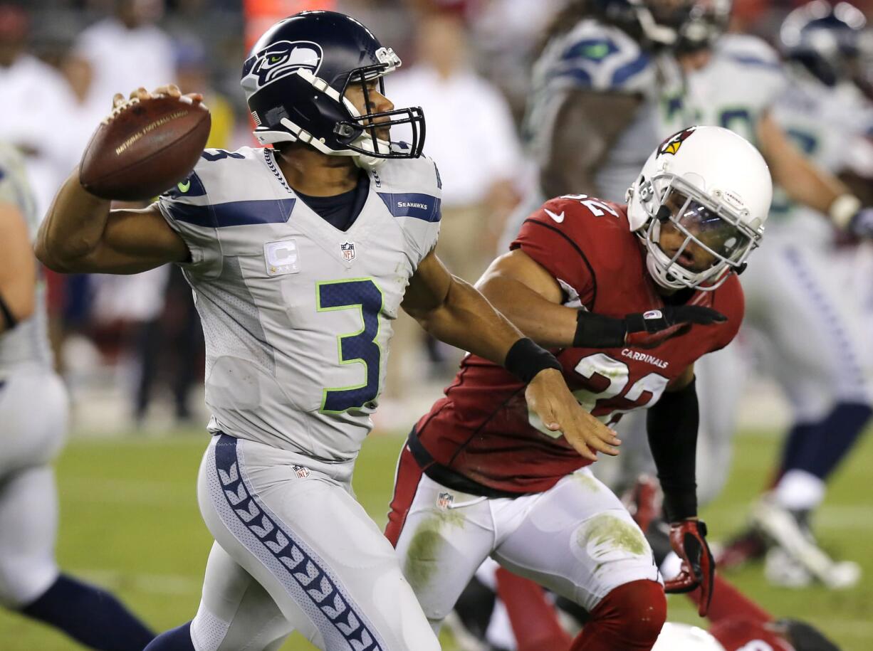 Seattle Seahawks quarterback Russell Wilson (3) scrambles as Arizona Cardinals free safety Tyrann Mathieu defends during the first half of an NFL football game, Thursday, Oct. 17, 2013, in Glendale, Ariz. (AP Photo/Ross D.