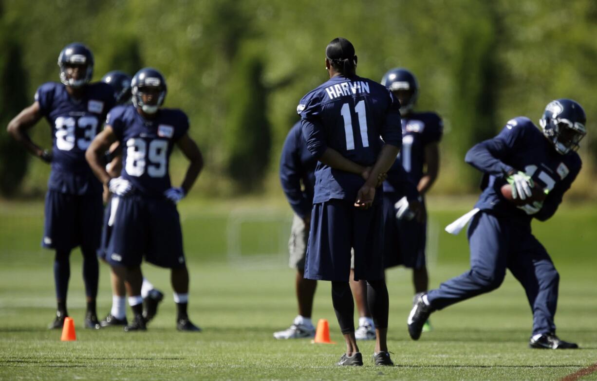 Injured Seattle Seahawks wide receiver Percy Harvin watches as other receivers go through practice drills during training camp on Saturday in Renton.