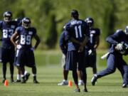 Injured Seattle Seahawks wide receiver Percy Harvin watches as other receivers go through practice drills during training camp on Saturday in Renton.