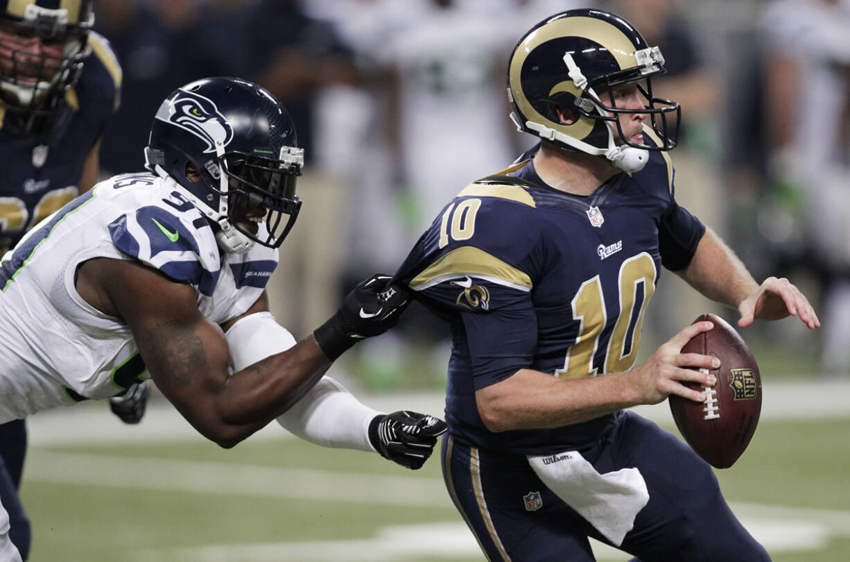 Seattle Seahawks defensive end Chris Clemons (91) grabs on to St. Louis Rams quarterback Kellen Clemens' jersey during the second half of an NFL football game, Monday, Oct. 28, 2013, in St. Louis.