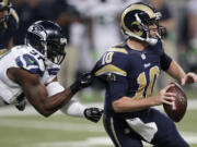 Seattle Seahawks defensive end Chris Clemons (91) grabs on to St. Louis Rams quarterback Kellen Clemens' jersey during the second half of an NFL football game, Monday, Oct. 28, 2013, in St. Louis.