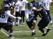 Seattle Seahawks top draft pick, running back Christine Michael, right, tries to avoid the defense of Seahawks' John Lotulelei, left, and Jaydan Bird, second from right, during practice drills Friday.