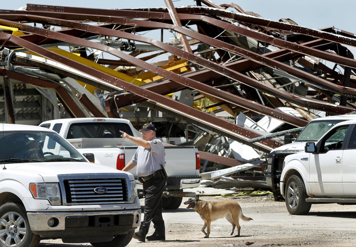 A police officer offers directions to a driver leaving this heavily damaged supply yard for Cactus Drilling Company on State Highway 66 in El Reno, Okla. on Saturday. Employee David Stottemyre was working in the lot when the tornado took aim at the plant. Stottemyre ran inside the large supply storage building and took shelter as the tornado passed over, leaving the building in a twisted pile of steel and metal.