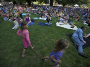 Amelia Wegner, 7, left in pink, walks off stage, along with 15-20 other children, after helping the Beatles tribute band Abbey Road with a rendition of Yellow Submarine during last year's Six to Sunset concert series kick off at Esther Short Park.