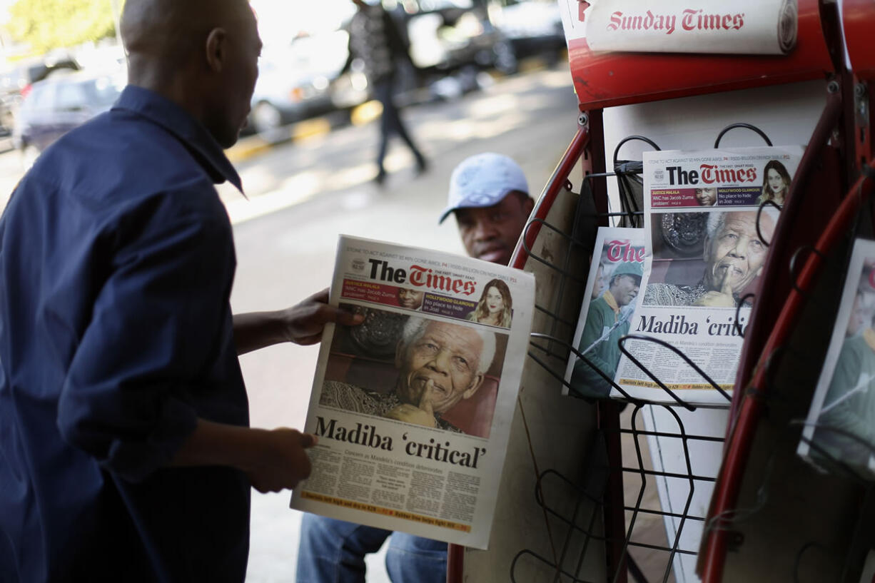 A man checks the headline of a South African newspaper reading &quot;Madiba Critical&quot; in a Johannesburg shopping mall Monday.