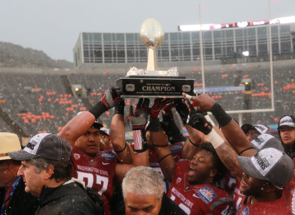 Washington State players hoist the Sun Bowl NCAA college football game trophy after defeating Miami 20-14 on Saturday, Dec. 26, 2015, in El Paso, Texas. Washington State ead coach Mike Leach, lower left, looks on.