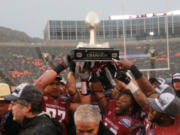 Washington State players hoist the Sun Bowl NCAA college football game trophy after defeating Miami 20-14 on Saturday, Dec. 26, 2015, in El Paso, Texas. Washington State ead coach Mike Leach, lower left, looks on.