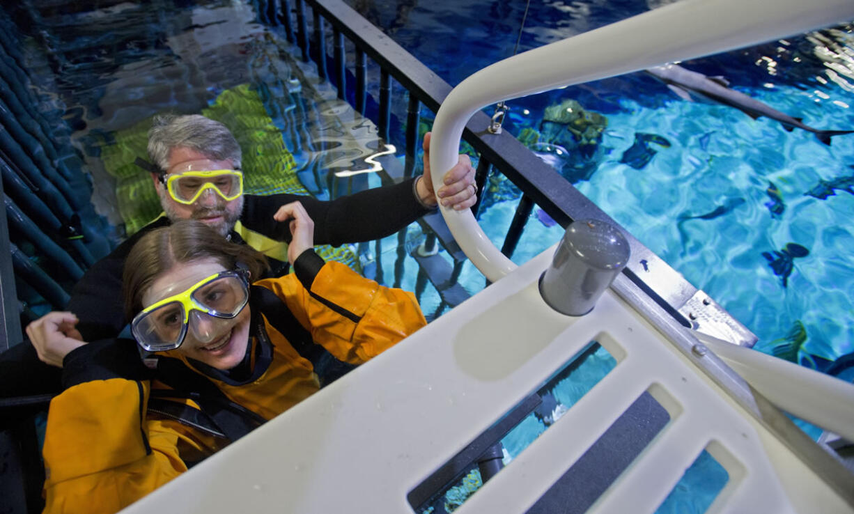 Head dive officer Gavin Wuttken, rear, helps Tacoma News Tribune reporter Stacia Glenn into shark-infested waters Thursday at the Point Defiance Zoo &amp; Aquarium as she got an up-close and personal view of sharks during a underwater cage dive, part of the zoo's new &quot;Eye-To-Eye Shark Dive&quot; adventure.