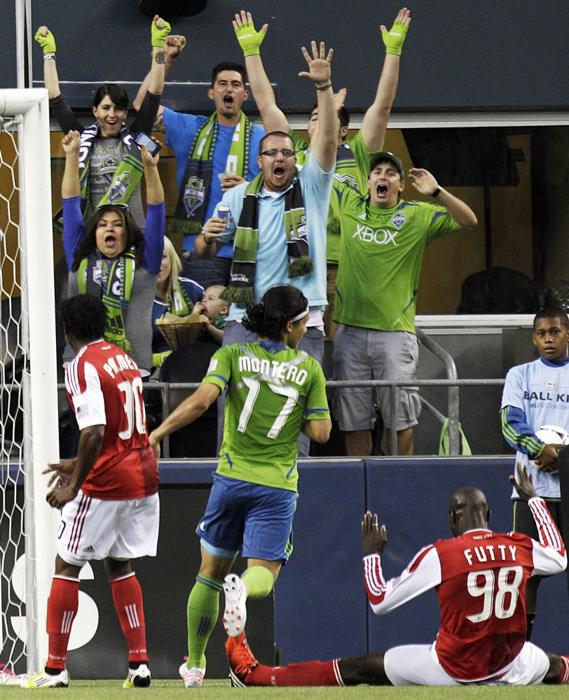 Seattle Sounders supporters celebrate with Fredy Montero (17) after Portland's Mamadou Danso (98) put the ball in his own goal in the 25th minute of Sunday's match.