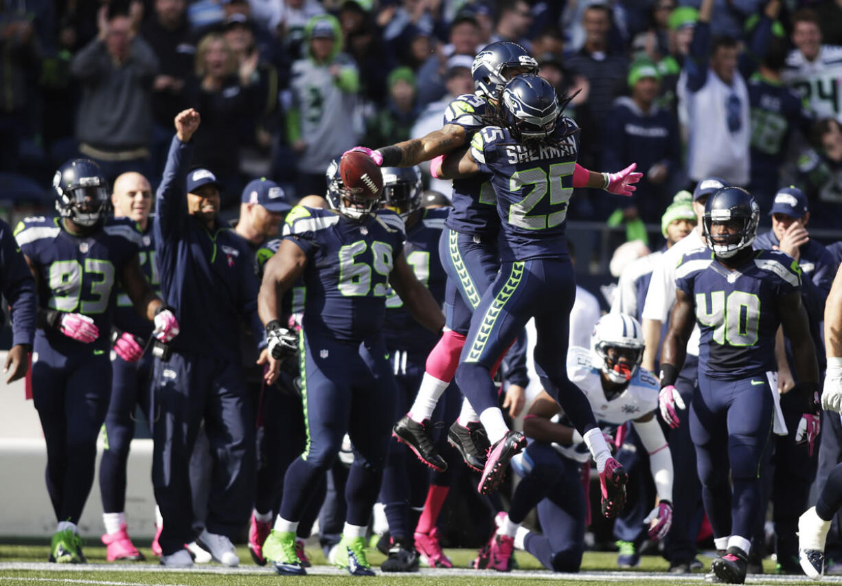 Seattle Seahawks' Richard Sherman (25) jumps and hugs Seahawks' Earl Thomas (29), center-left, after Thomas intercepted a pass in the first half of an NFL football game against the Tennessee Titans, Sunday, Oct. 13, 2013, in Seattle.