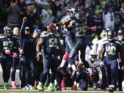 Seattle Seahawks' Richard Sherman (25) jumps and hugs Seahawks' Earl Thomas (29), center-left, after Thomas intercepted a pass in the first half of an NFL football game against the Tennessee Titans, Sunday, Oct. 13, 2013, in Seattle.