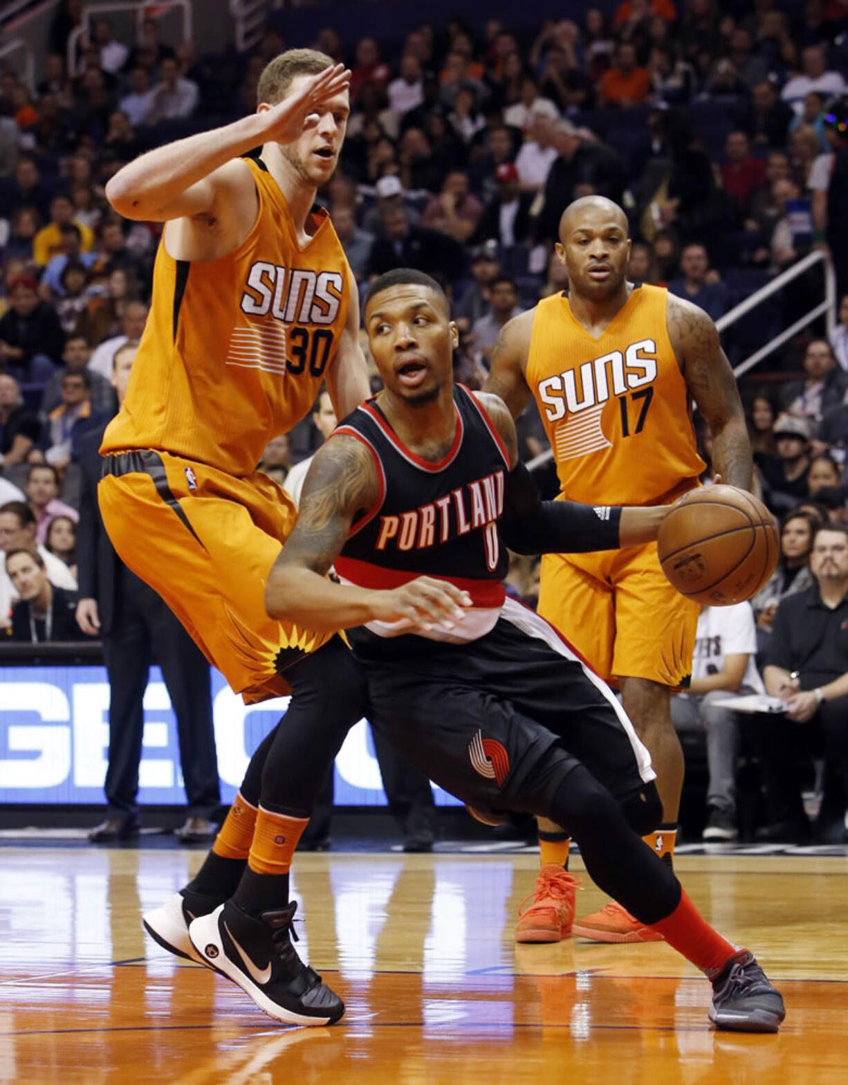 Portland Trail Blazers guard Damian Lillard (0) drives past Phoenix Suns forward Jon Leuer (30) in the first quarter during an NBA basketball game, Friday, Dec. 11, 2015, in Phoenix.