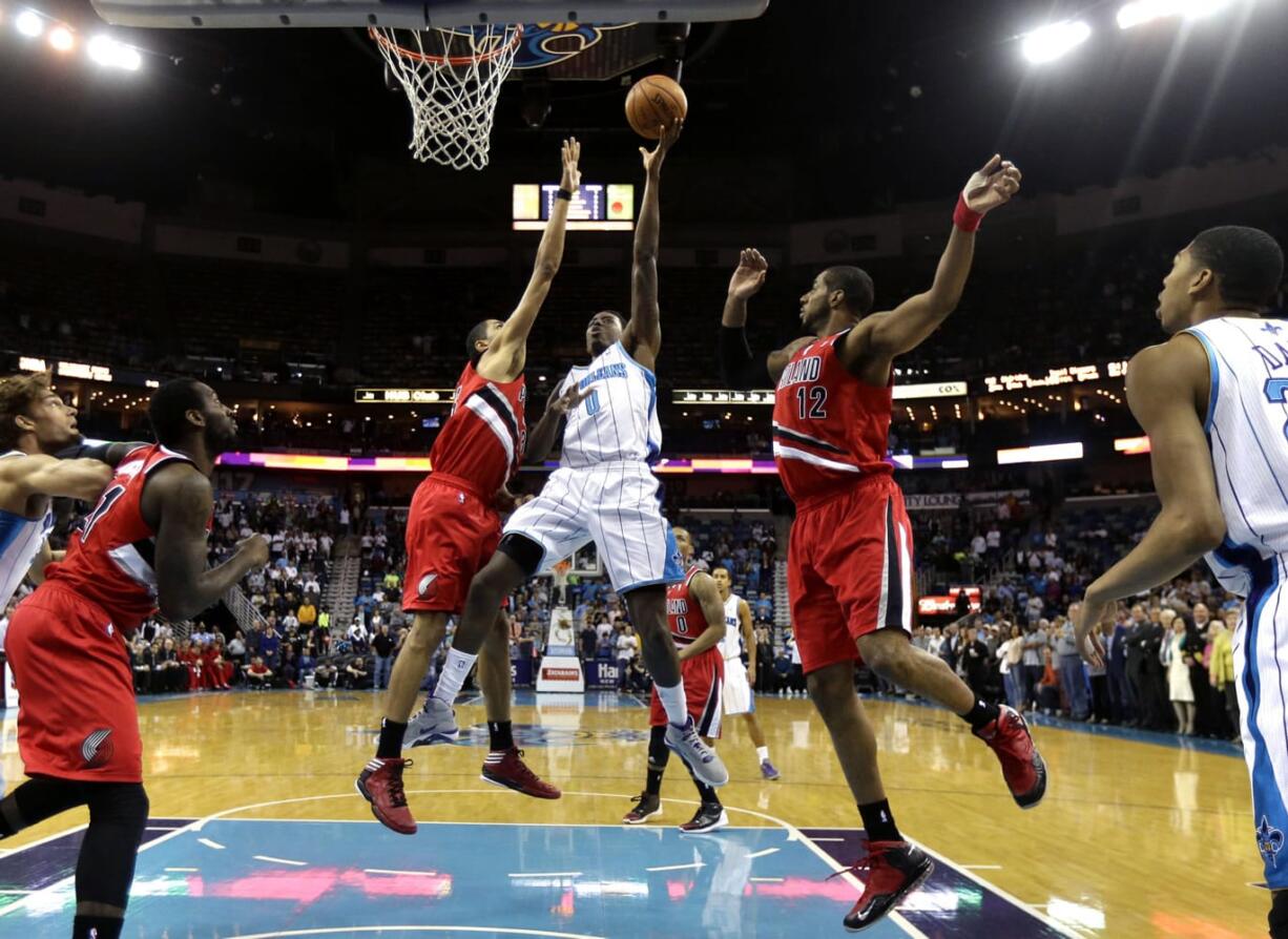 New Orleans Hornets forward Al-Farouq Aminu (0) shoots between Portland Trail Blazers forward LaMarcus Aldridge (12) and forward Nicolas Batum, left,  in the first half of an NBA basketball game in New Orleans, Sunday, March 10, 2013.