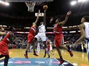 New Orleans Hornets forward Al-Farouq Aminu (0) shoots between Portland Trail Blazers forward LaMarcus Aldridge (12) and forward Nicolas Batum, left,  in the first half of an NBA basketball game in New Orleans, Sunday, March 10, 2013.