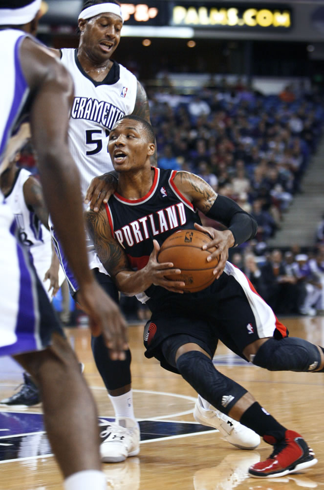 Portland Trail Blazers guard Damian Lillard, right, drives to the basket around Sacramento Kings defender James Johnson during the first half Sunday.