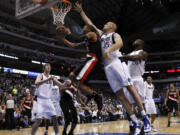 Portland Trail Blazers' Damian Lillard, center, goes up for a shot as Dallas Mavericks' Vince Carter (25) defends during the first half Monday.